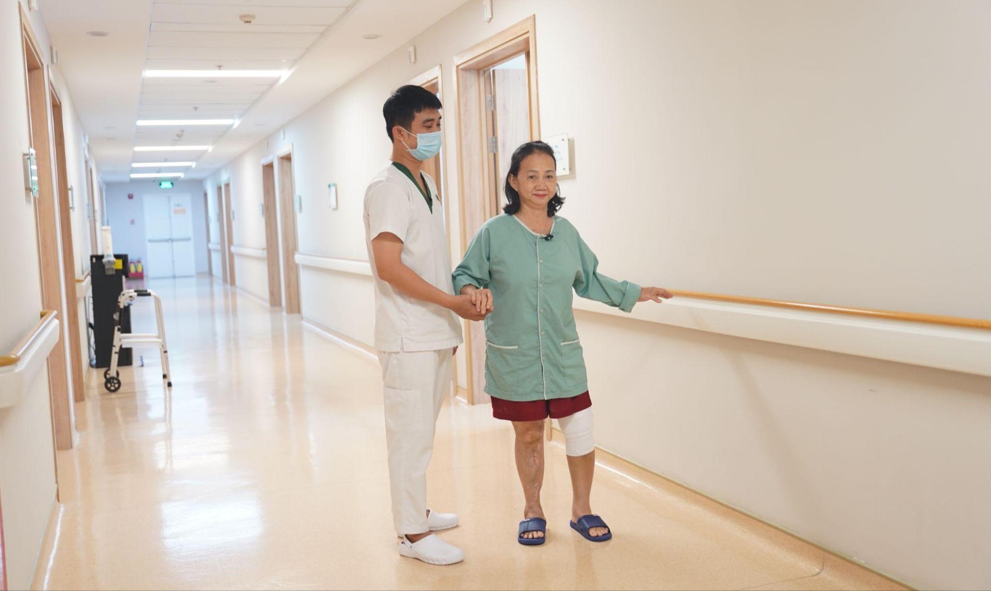 在工作人员的搀扶下，患者站立并行走